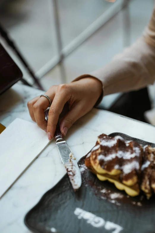 the hand is using the knife to cut a plate of food