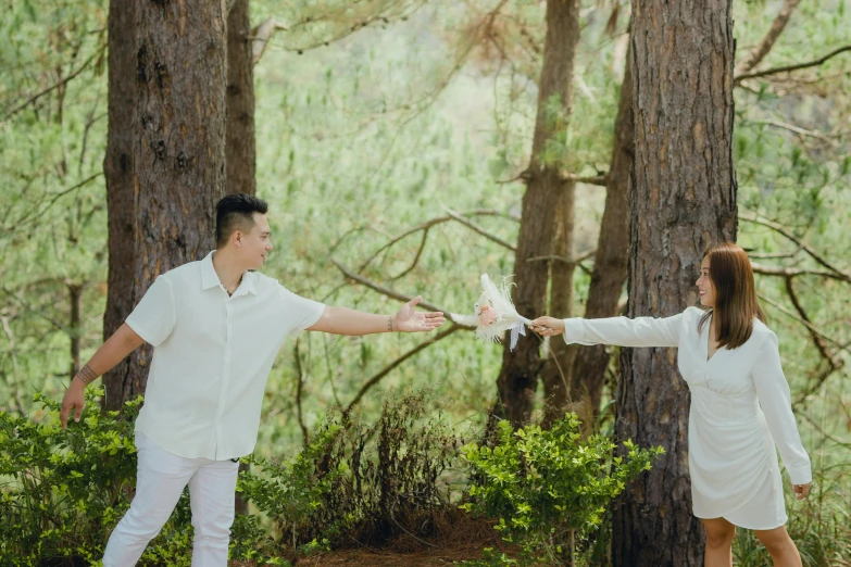 this is a couple in the woods with one holding a white object