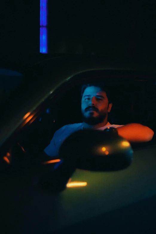 a man leans on a car in the dark