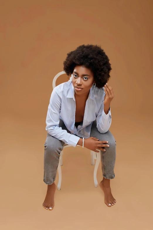 a woman in jeans is sitting on a chair