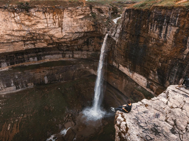 two people sitting at the top of a waterfall