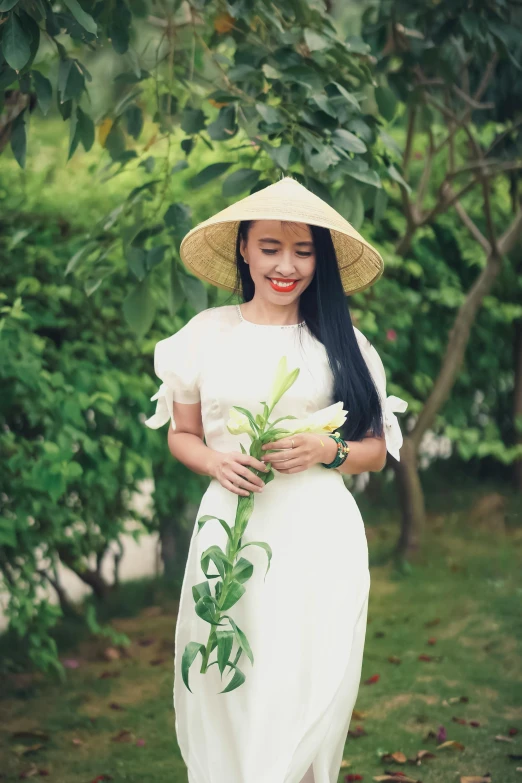 a woman wearing a hat and holding a flower