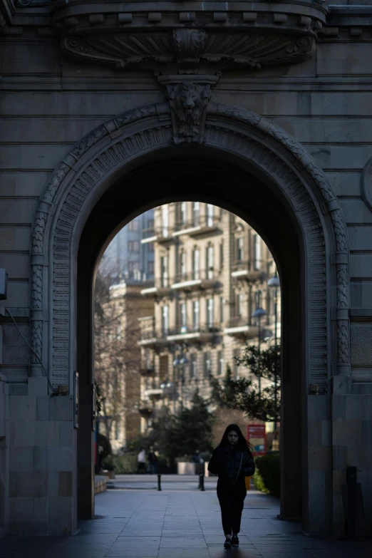 the person is walking towards a building through the tunnel