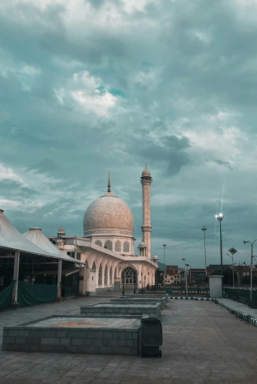 an old mosque and a monument are pictured under cloudy skies