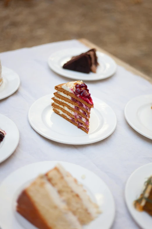 a variety of cakes on some plates arranged on a table