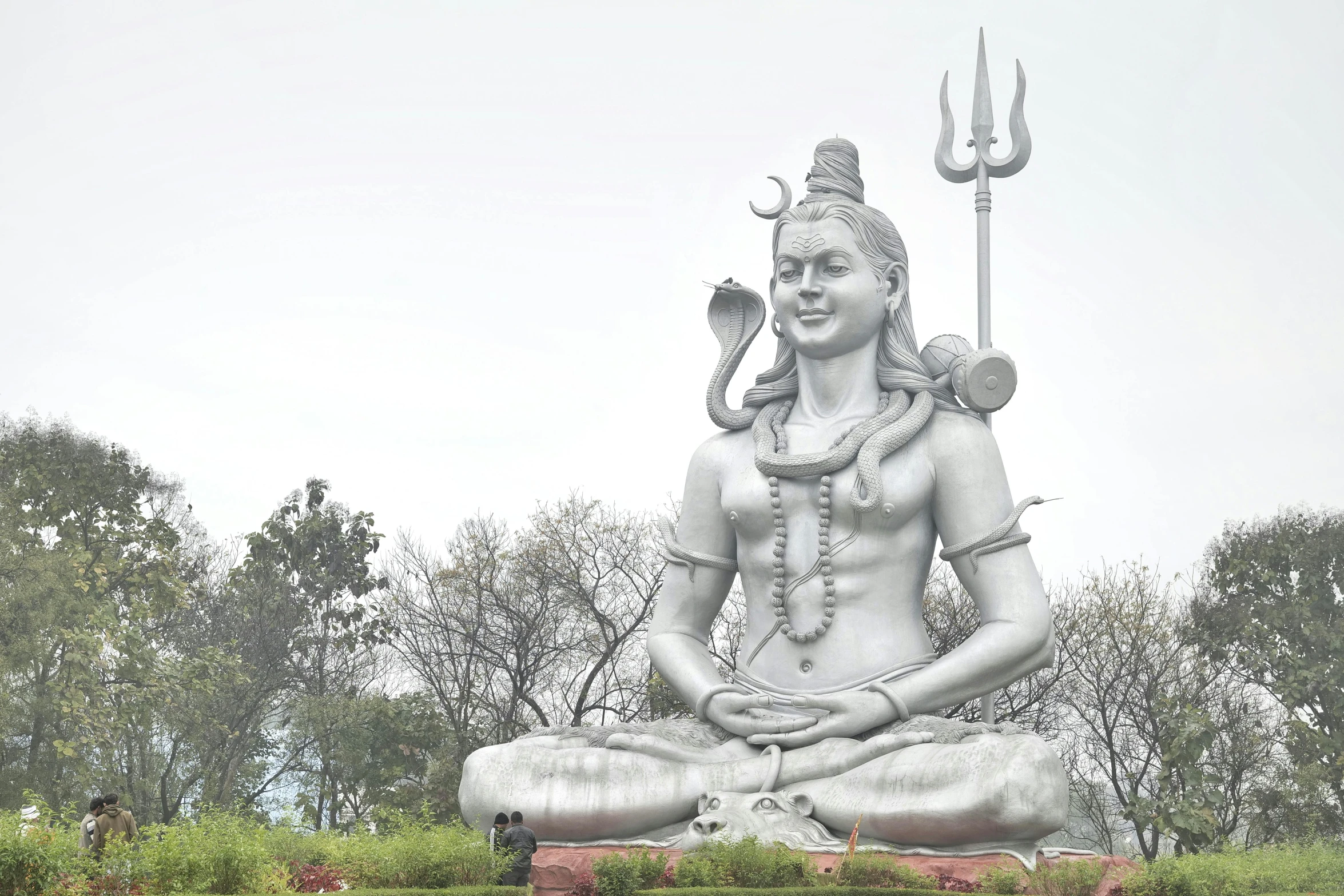 a large statue sits outside near some trees