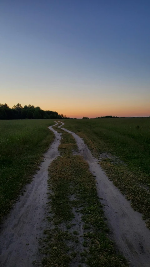 dirt road at sunset leading to another grassy area