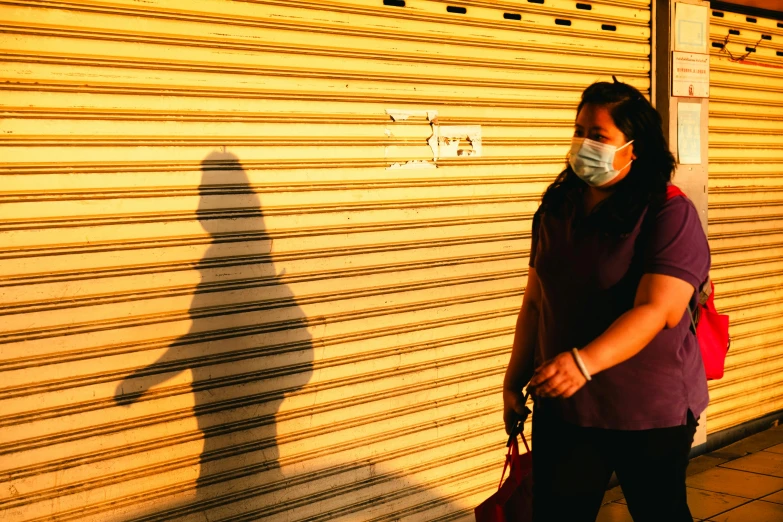 a woman standing outside wearing a mask and carrying a suitcase