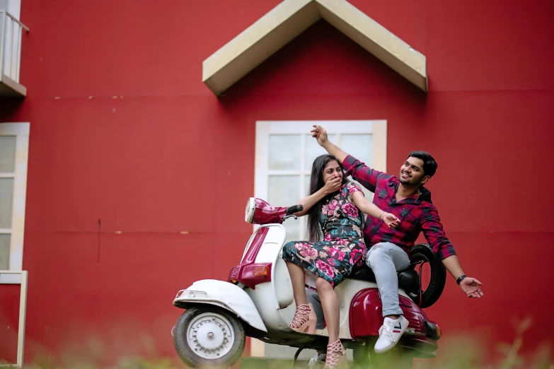 a couple rides on top of a small motor scooter