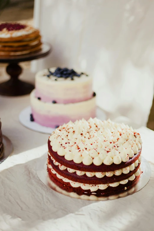 three cakes covered with white and red icing