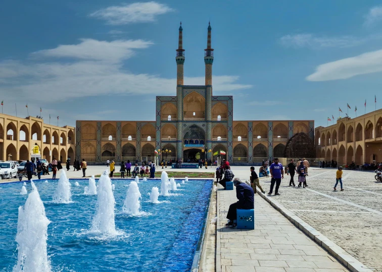 tourists at the entrance to a large building with a fountain in front