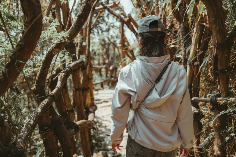 a man in a white sweatshirt looks down a forest