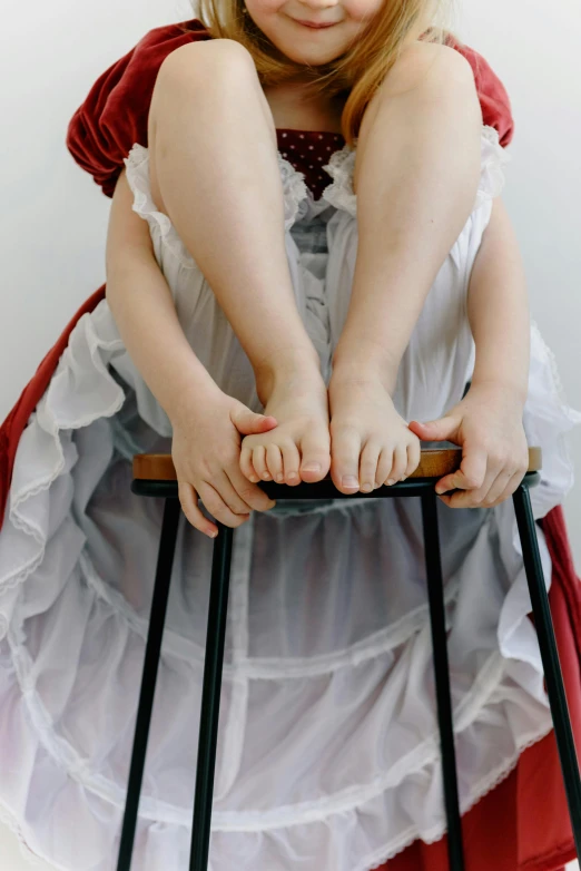 a little girl is on top of a chair with her legs folded