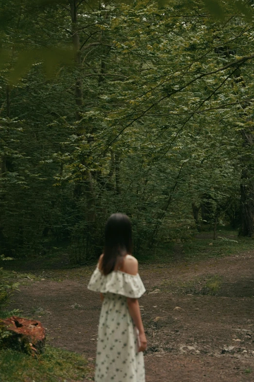 a woman walking down a trail near trees