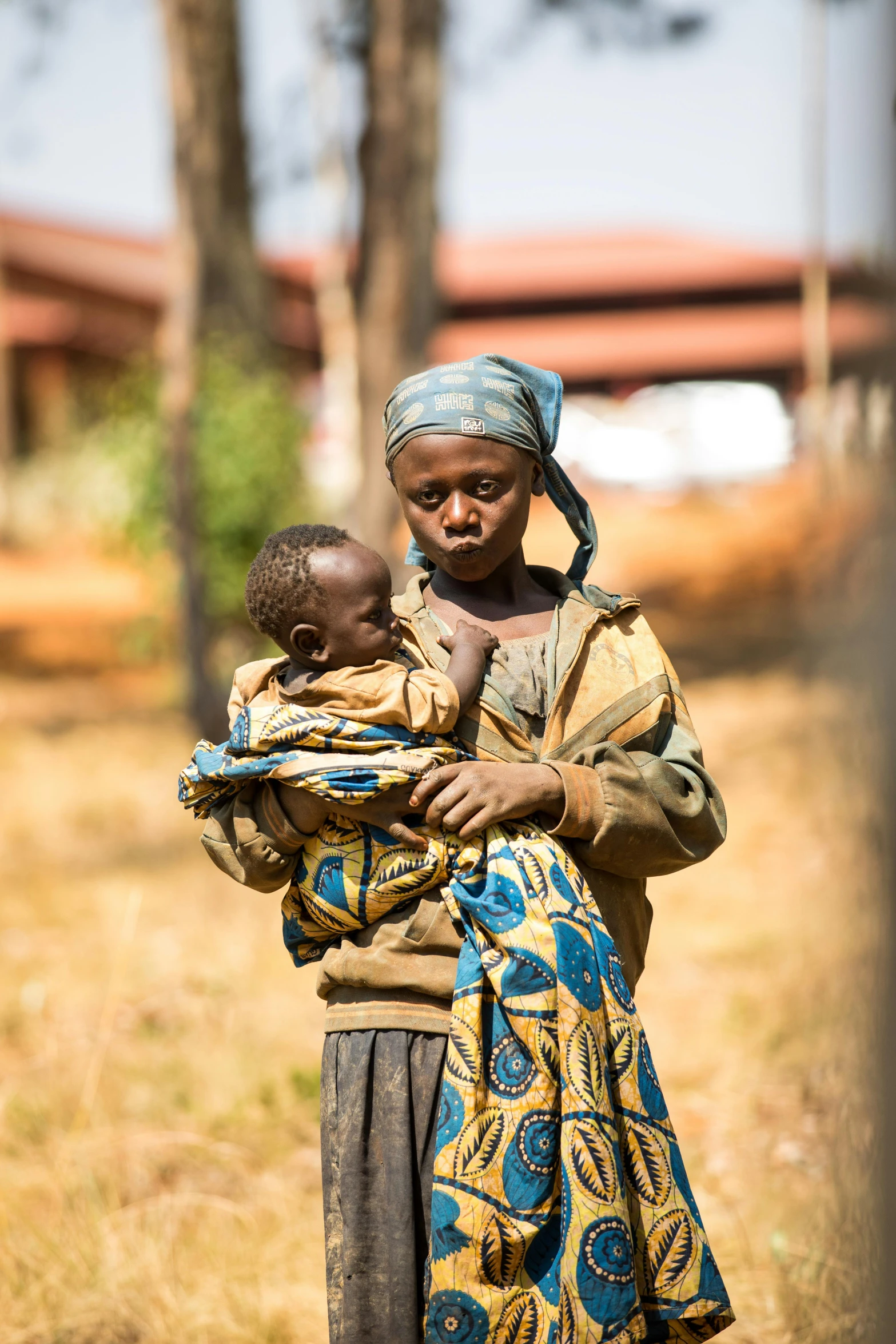 woman carrying a child in her arms and looking at camera