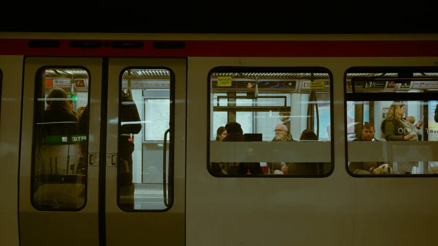 people sit inside of a subway car, and a few have their faces close