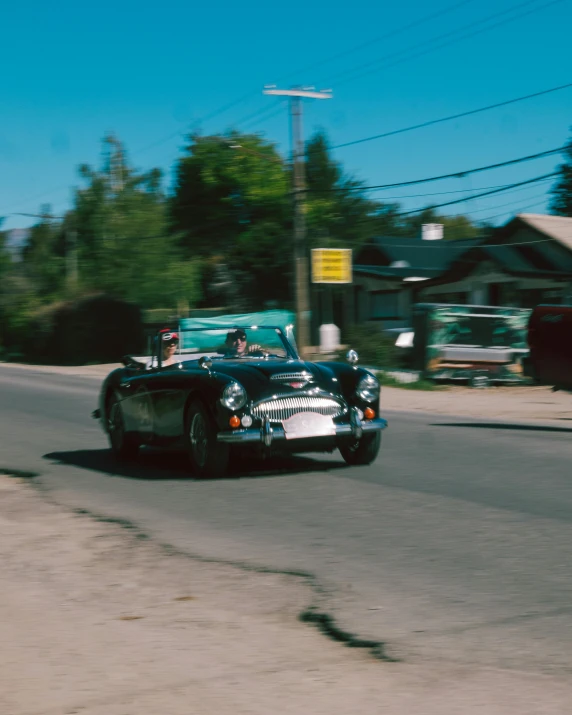 old vintage cars driving down the road during the day