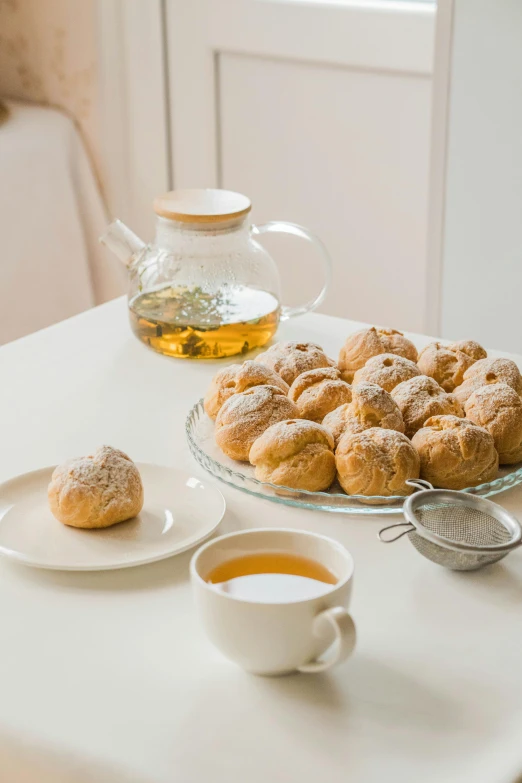 a white table topped with plates and a serving tray full of donuts