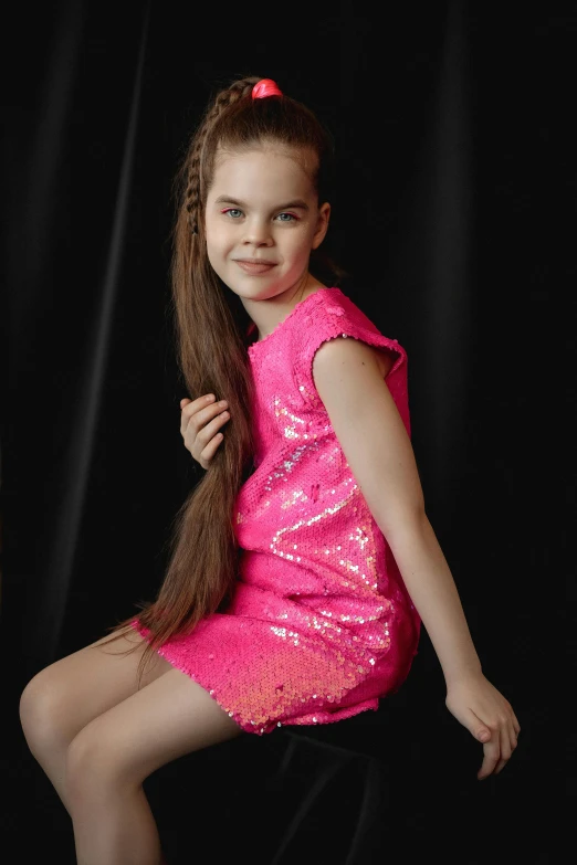 a little girl in a pink dress and black background