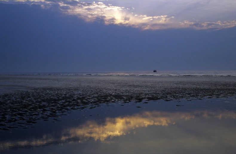 some sand water and clouds and a boat