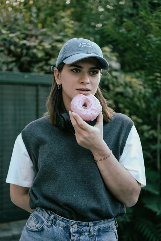 a woman standing outside and holding a doughnut in her hands