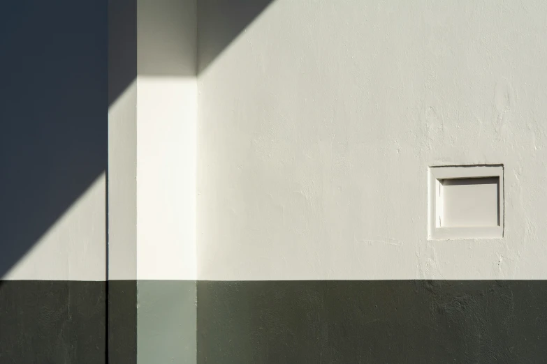 the shadows from the top of the wall are cast over a corner with a small window