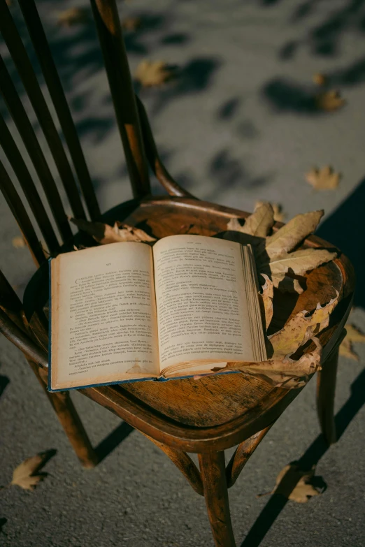 an open book is sitting in a wooden chair