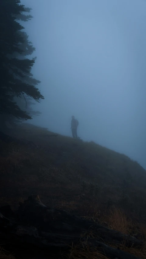 the silhouette of a person standing on top of a mountain in a fog