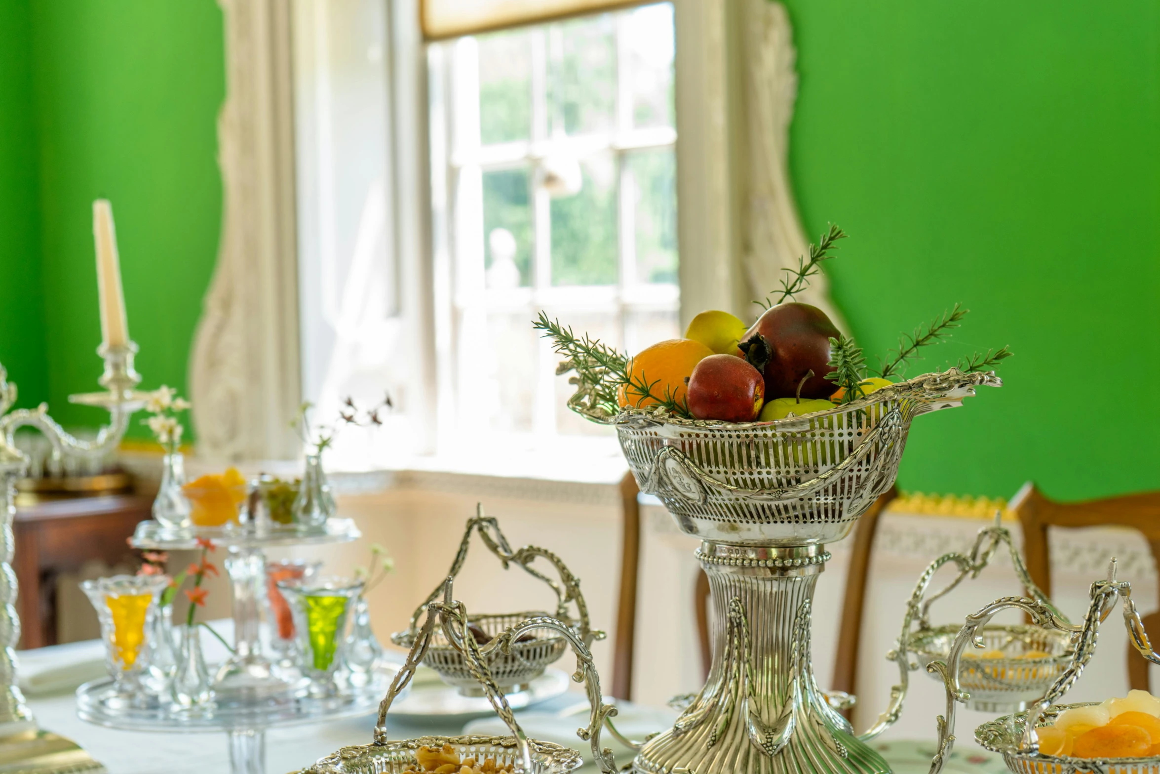 an elegant silver vase filled with fruit sitting on top of a table