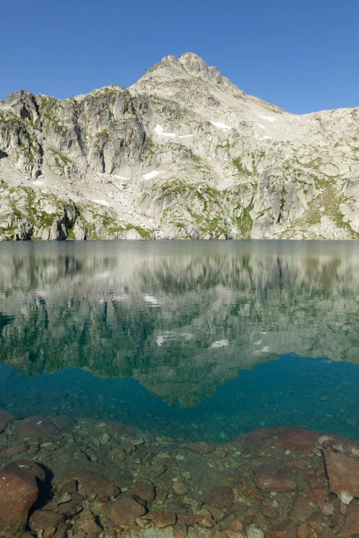 a clear blue lake with a mountain in the background