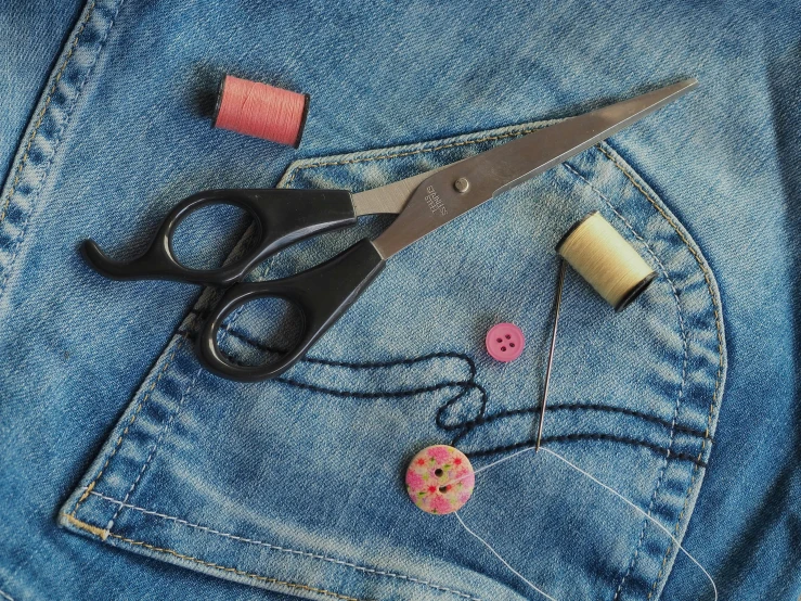 sewing materials laid out in the back pocket of denim jacket