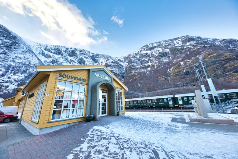 a train that is passing by a yellow building