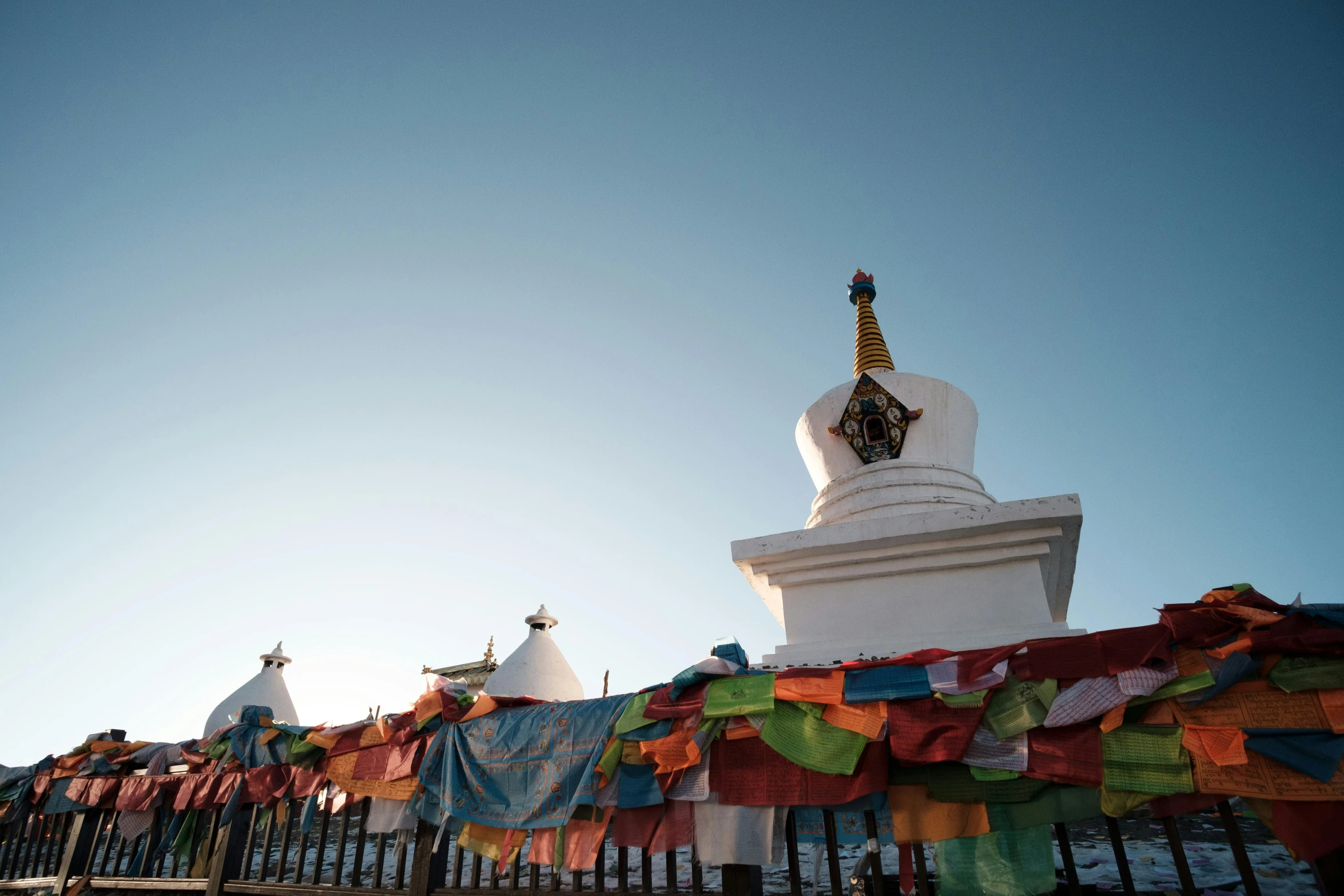 a row of flags and a small statue with a clock tower behind