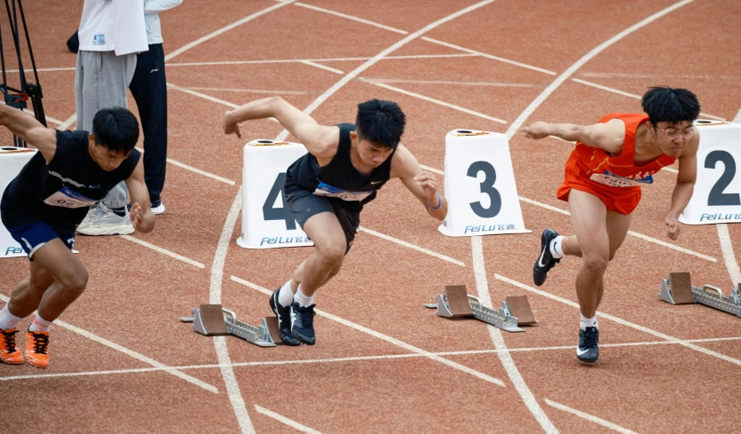 two men in running uniforms on the starting line of a track