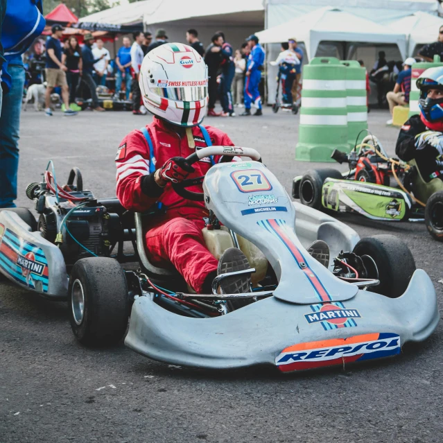 a young man driving a silver race car