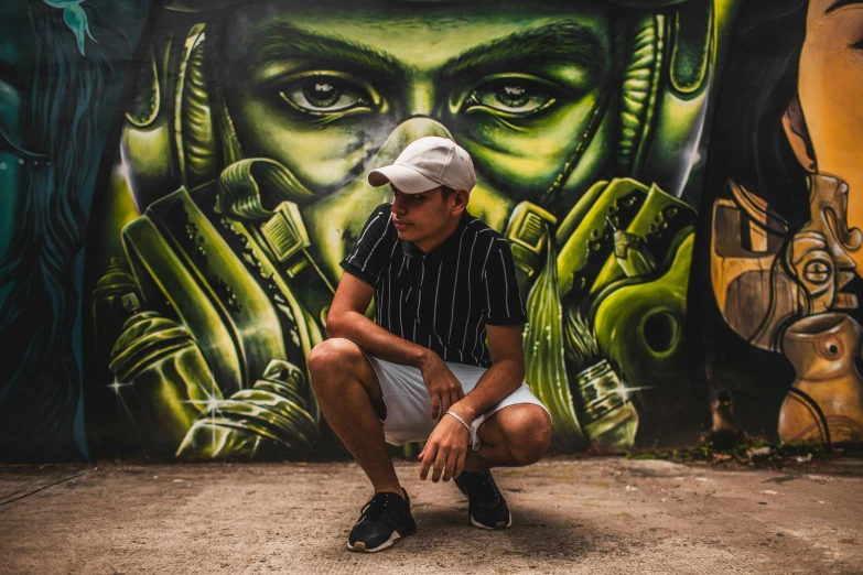 man sitting in front of a graffiti wall with a gun and face painted