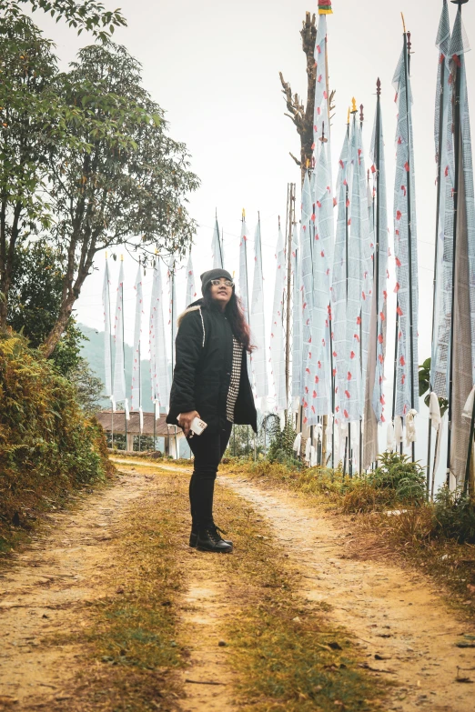 a person wearing a black jacket is posing in front of flags