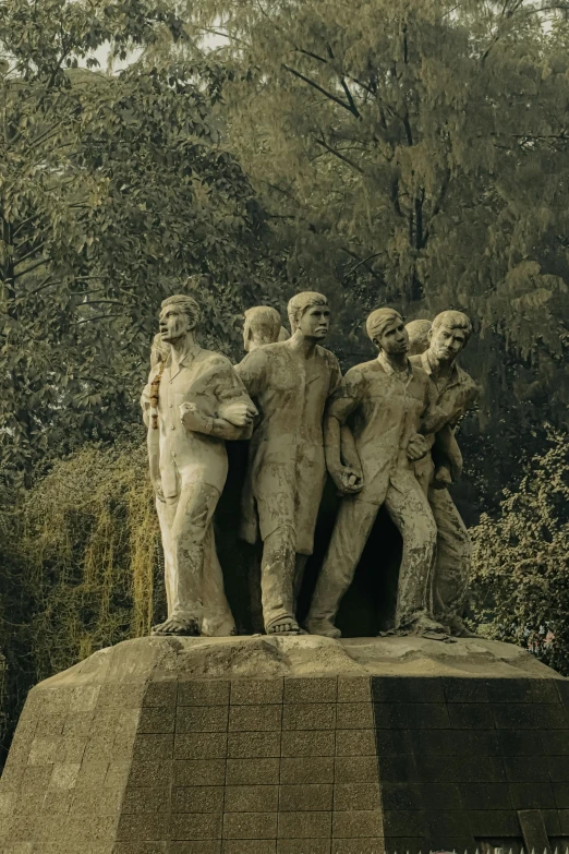 some statues are standing on a mound near trees