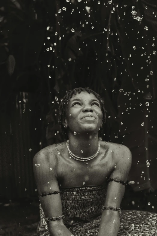 a woman smiling and sitting on the ground while raining