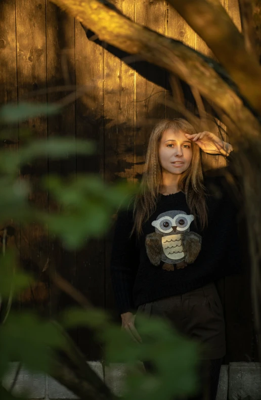 a girl standing near a building with an owl shirt on