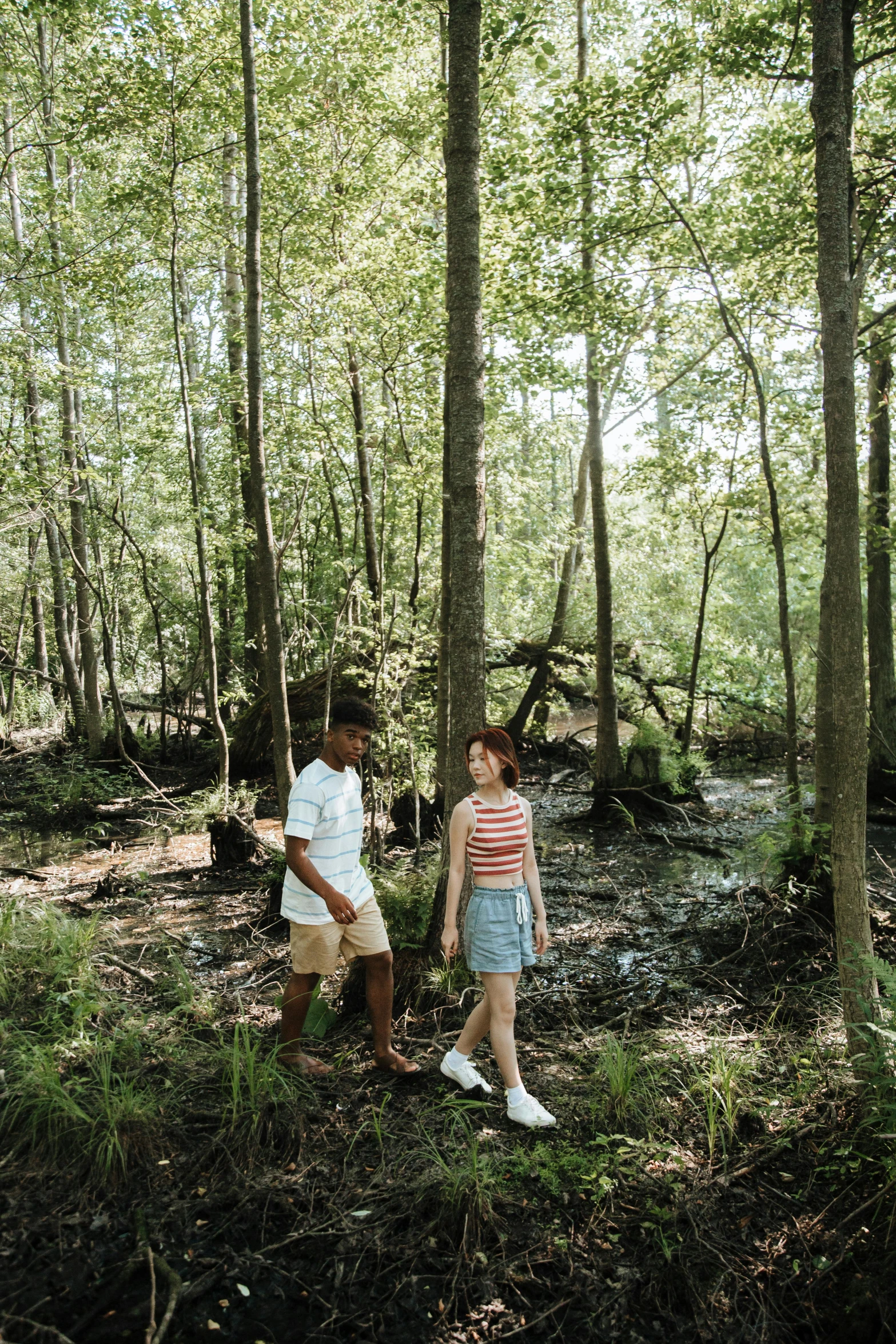 two children standing in a forest near a stream