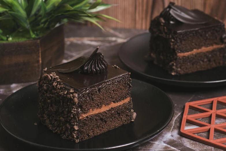 two black plates holding a slice of chocolate cake