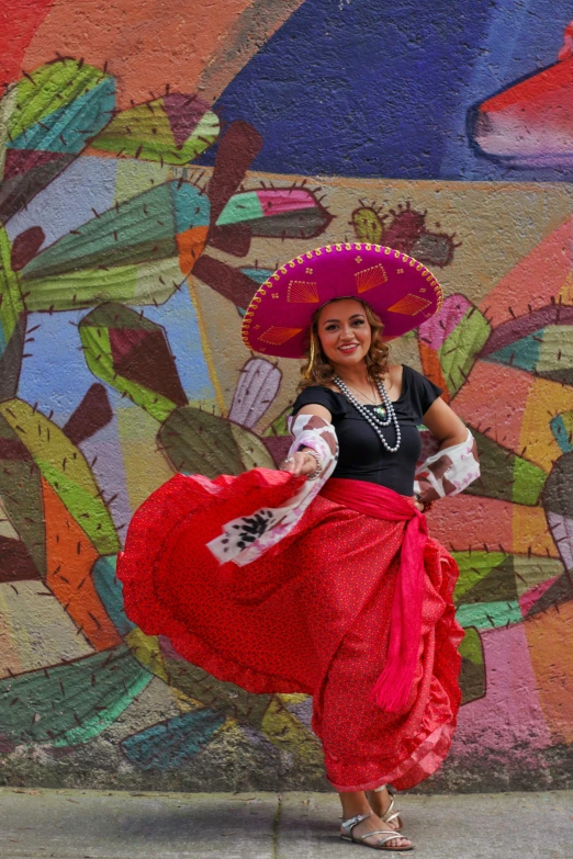 a woman in a mexican dress dancing next to a painted wall