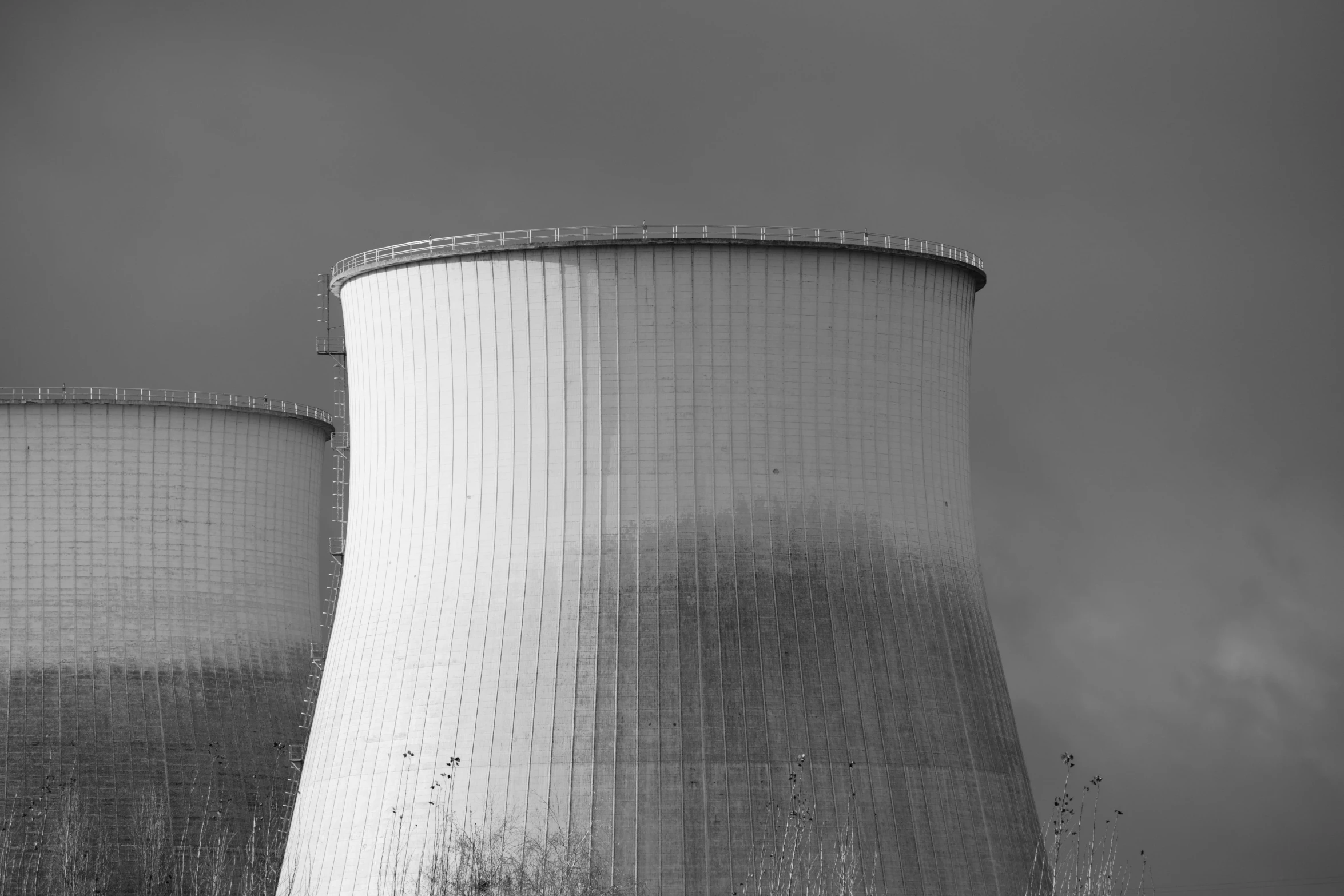 two cooling towers sitting under cloudy skies on top of a building