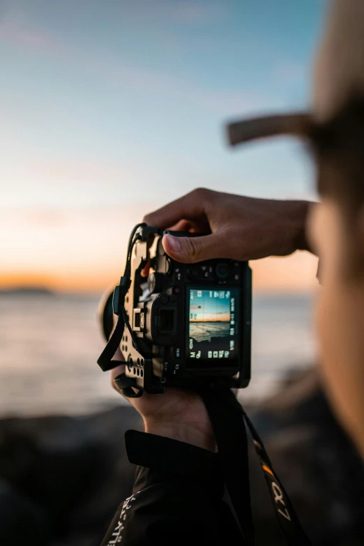 a person is holding a camera at the beach