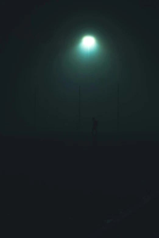 an foggy field with a person walking in the distance