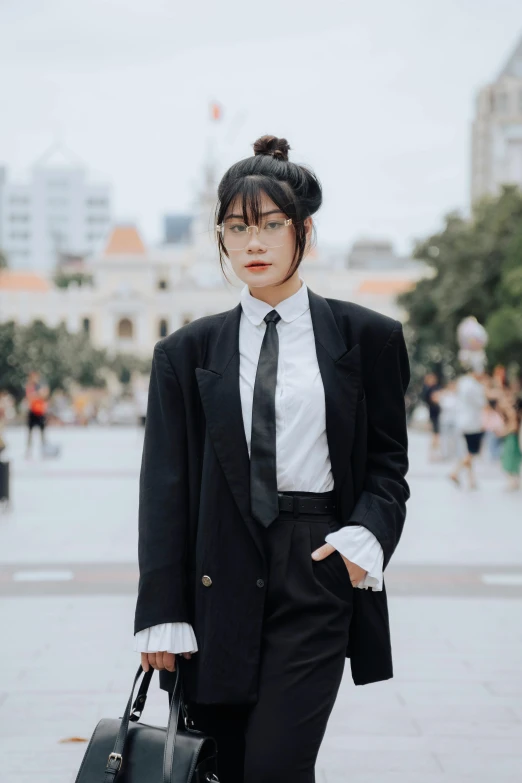 woman in black suit and tie with black handbag