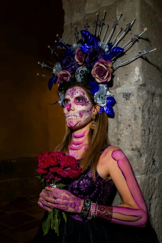 a woman in makeup holds roses against a rock