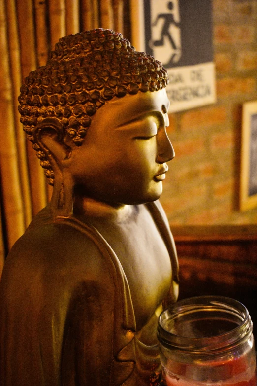 a wooden statue of buddha holding a jar of jam