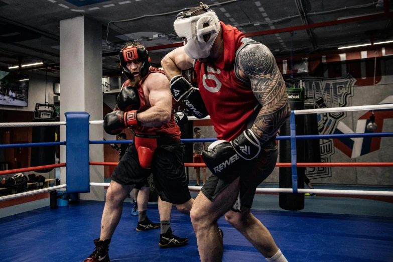 two men with tattoos and a mask in a boxing ring